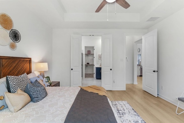 2705 Sage Ranch Dr Unit 19, Leander, TX 78641 - bedroom with a tray ceiling, light wood finished floors, connected bathroom, and a ceiling fan