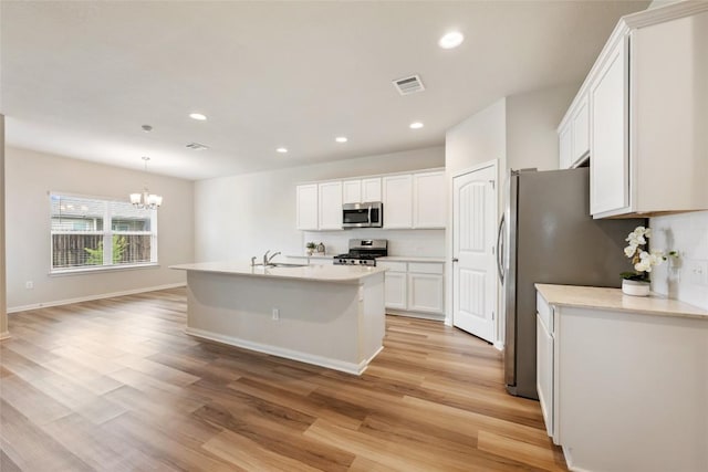 2533 Buffalo Ford Ct, Georgetown, TX 78628 - kitchen with appliances with stainless steel finishes, a chandelier, white cabinetry, light wood-type flooring, and recessed lighting