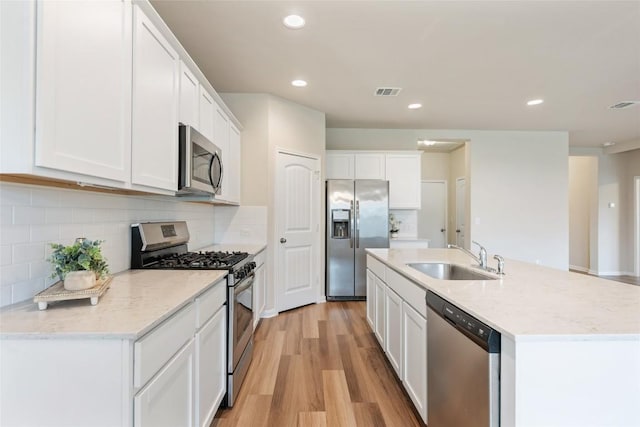 2533 Buffalo Ford Ct, Georgetown, TX 78628 - kitchen featuring stainless steel appliances, light wood finished floors, white cabinetry, a center island with sink, and recessed lighting