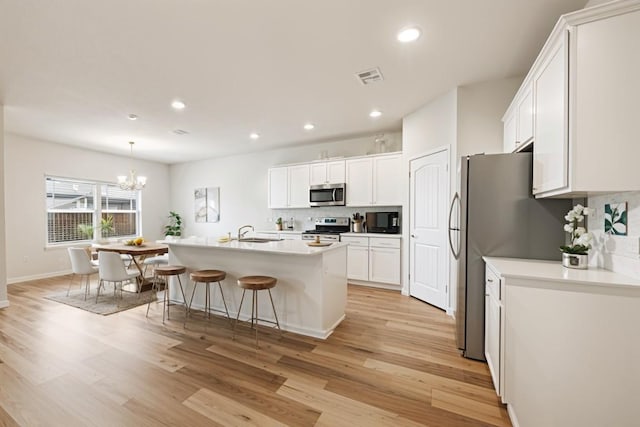2533 Buffalo Ford Ct, Georgetown, TX 78628 - kitchen featuring appliances with stainless steel finishes, backsplash, light wood-type flooring, white cabinets, and recessed lighting