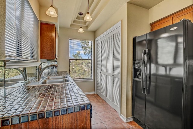 8200 Neely Dr Unit 116, Austin, TX 78759 - kitchen with black fridge, tile counters, pendant lighting, brown cabinets, and light tile patterned flooring
