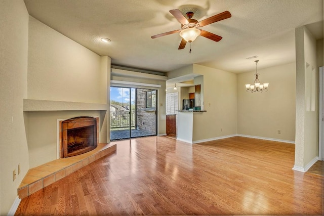 8200 Neely Dr Unit 116, Austin, TX 78759 - unfurnished living room with a tiled fireplace, wood finished floors, a chandelier, and a ceiling fan