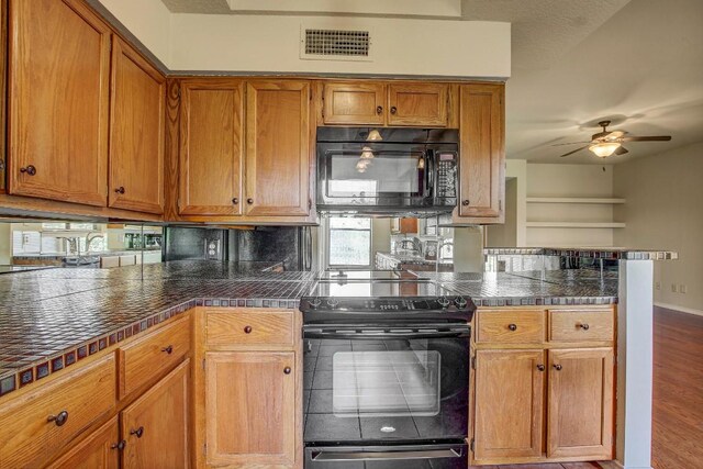 8200 Neely Dr Unit 116, Austin, TX 78759 - kitchen featuring black appliances, brown cabinets, dark countertops, a ceiling fan, and wood finished floors
