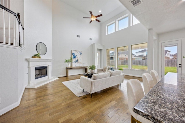 19612 Abigail Way, Pflugerville, TX 78660 - living room featuring hardwood / wood-style floors, ceiling fan, a fireplace with raised hearth, and a towering ceiling