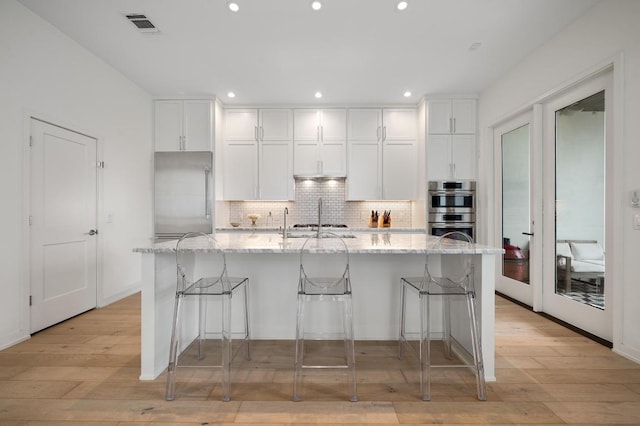 2608 Watkins Way, Austin, TX 78746 - kitchen with appliances with stainless steel finishes, white cabinetry, tasteful backsplash, recessed lighting, and a large island