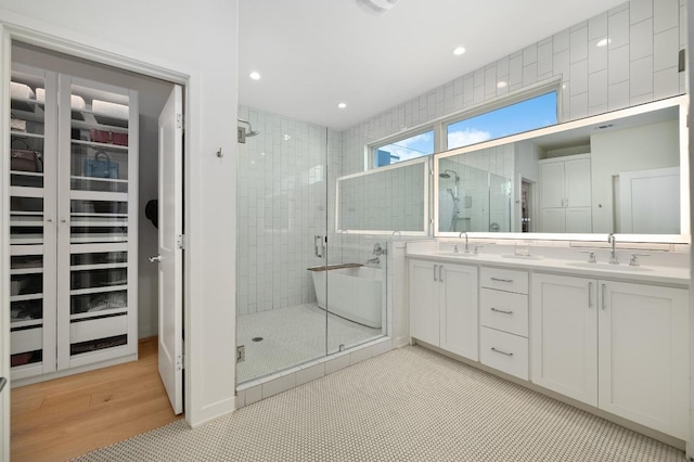 2608 Watkins Way, Austin, TX 78746 - full bathroom with a shower stall, double vanity, a walk in closet, wood finished floors, and recessed lighting