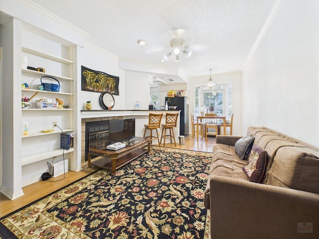 3111 Tom Green St Unit 208, Austin, TX 78705 - living area featuring ornamental molding, a textured ceiling, wood finished floors, a tile fireplace, and built in features
