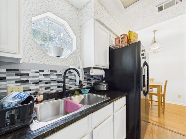 3111 Tom Green St Unit 208, Austin, TX 78705 - kitchen with black fridge, white cabinets, light wood-style flooring, decorative backsplash, and dark countertops