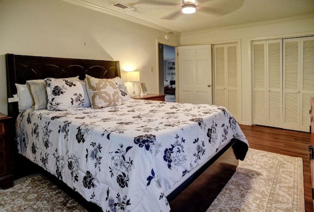 4703 Laguna Ln, Austin, TX 78746 - bedroom with wood finished floors, ornamental molding, multiple closets, ceiling fan, and a textured ceiling
