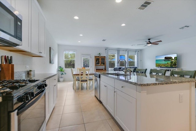 229 Mary Max Cir, San Marcos, TX 78666 - kitchen with stainless steel appliances, dark stone counters, white cabinetry, a center island with sink, and recessed lighting