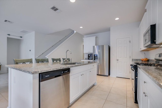 229 Mary Max Cir, San Marcos, TX 78666 - kitchen with appliances with stainless steel finishes, light tile patterned floors, a center island with sink, white cabinetry, and light stone countertops