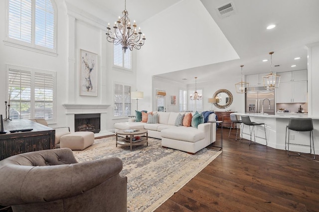 11208 Woodland Hills Trl, Austin, TX 78732 - living room featuring a chandelier, dark wood-style flooring, a high ceiling, recessed lighting, and a fireplace with raised hearth