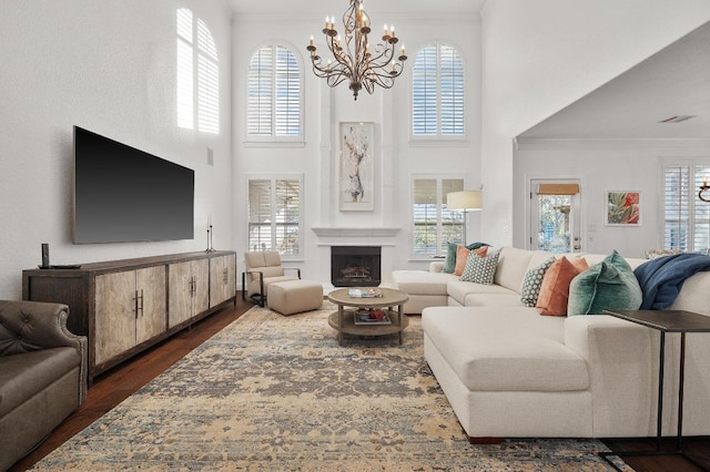 11208 Woodland Hills Trl, Austin, TX 78732 - living room with a chandelier, ornamental molding, dark wood-type flooring, a fireplace, and a towering ceiling