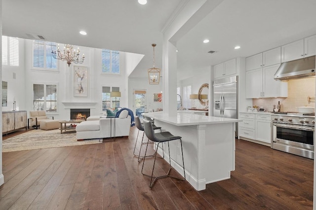 11208 Woodland Hills Trl, Austin, TX 78732 - kitchen featuring high quality appliances, extractor fan, a chandelier, dark wood-style flooring, and a high ceiling