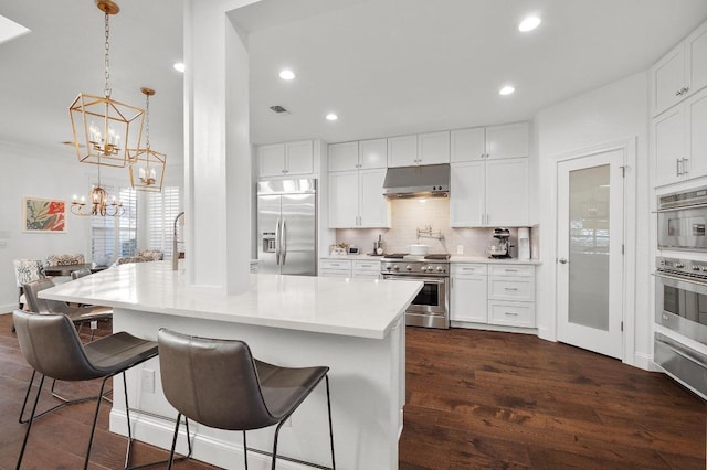 11208 Woodland Hills Trl, Austin, TX 78732 - kitchen featuring premium appliances, under cabinet range hood, dark wood-style floors, backsplash, and recessed lighting