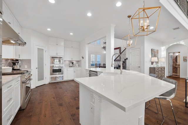 11208 Woodland Hills Trl, Austin, TX 78732 - kitchen featuring stainless steel appliances, a warming drawer, a chandelier, decorative backsplash, and dark wood-style floors