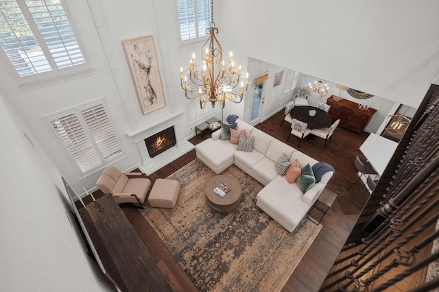11208 Woodland Hills Trl, Austin, TX 78732 - living area featuring a chandelier, a towering ceiling, wood finished floors, healthy amount of natural light, and a warm lit fireplace