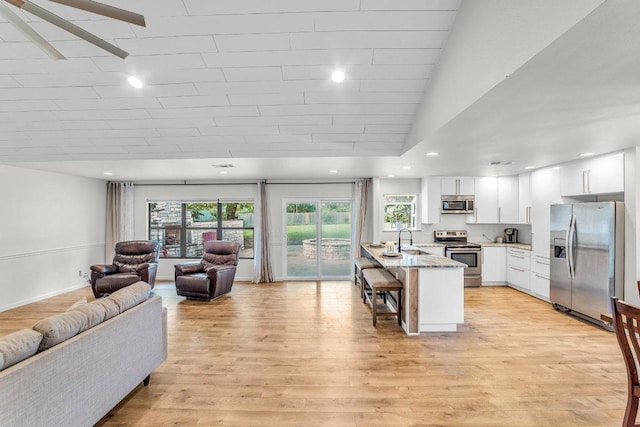 3705 Peach Vista Dr, Pflugerville, TX 78660 - kitchen with stainless steel appliances, a peninsula, open floor plan, a kitchen bar, and white cabinetry
