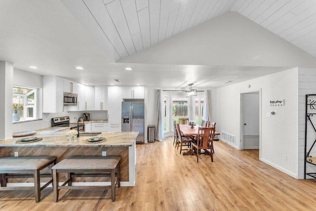 3705 Peach Vista Dr, Pflugerville, TX 78660 - kitchen featuring appliances with stainless steel finishes, a peninsula, white cabinets, light wood finished floors, and lofted ceiling
