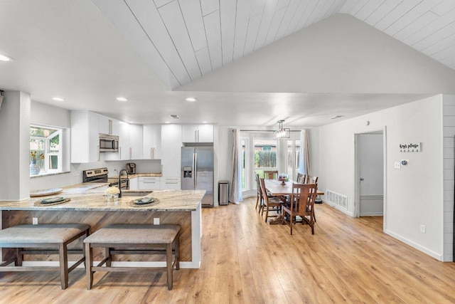 3705 Peach Vista Dr, Pflugerville, TX 78660 - kitchen featuring stainless steel appliances, a peninsula, white cabinets, vaulted ceiling, and healthy amount of natural light