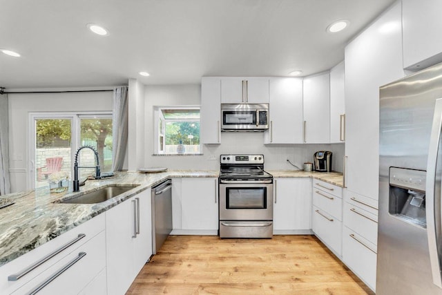 3705 Peach Vista Dr, Pflugerville, TX 78660 - kitchen featuring appliances with stainless steel finishes, light wood-style floors, white cabinets, tasteful backsplash, and recessed lighting