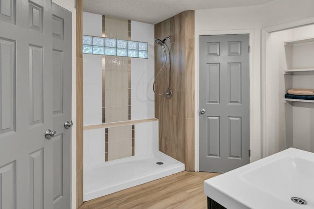 3705 Peach Vista Dr, Pflugerville, TX 78660 - bathroom with tiled shower, a textured ceiling, and wood finished floors