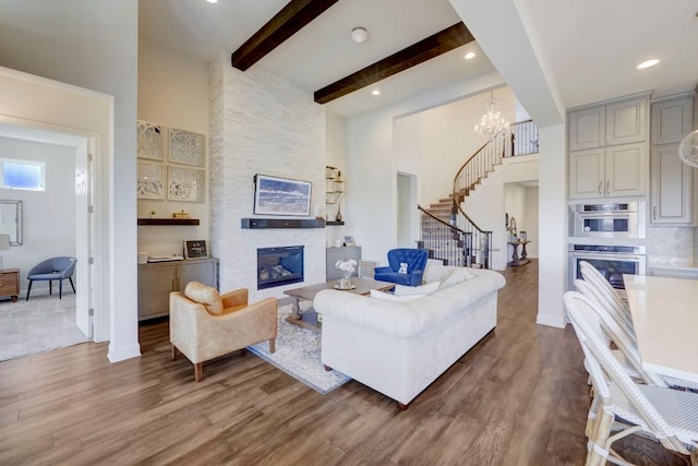 6701 Denia Dr, Austin, TX 78739 - living room with stairs, beamed ceiling, wood finished floors, a stone fireplace, and a towering ceiling