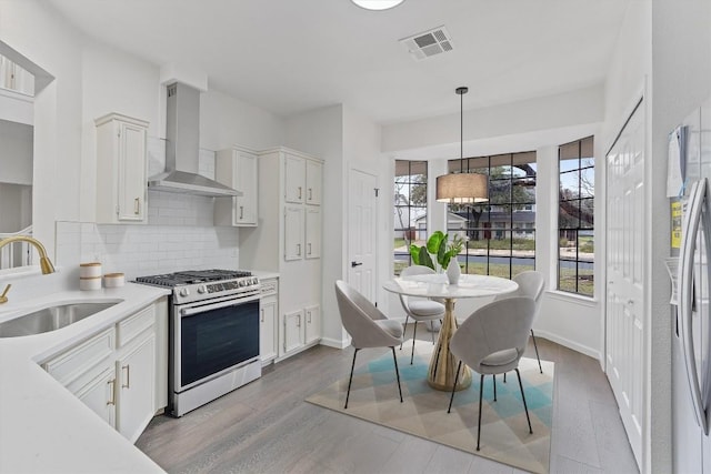 7401 Whistlestop Dr, Austin, TX 78749 - kitchen with appliances with stainless steel finishes, wall chimney exhaust hood, light countertops, decorative backsplash, and hanging light fixtures