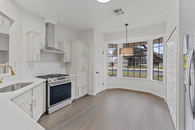 7401 Whistlestop Dr, Austin, TX 78749 - kitchen with stainless steel appliances, wall chimney range hood, light countertops, tasteful backsplash, and wood finished floors