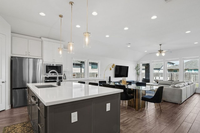 14521 Kira Ln, Manor, TX 78653 - kitchen featuring appliances with stainless steel finishes, dark wood finished floors, a ceiling fan, a center island with sink, and light countertops