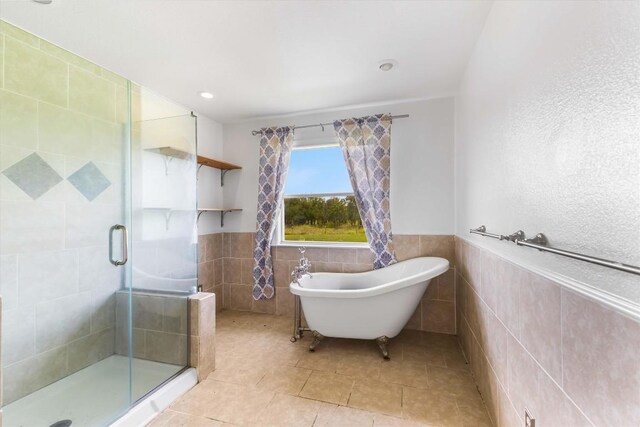 12212 Ballerstedt Rd, Elgin, TX 78621 - bathroom featuring tile walls, a shower stall, a soaking tub, tile patterned floors, and wainscoting