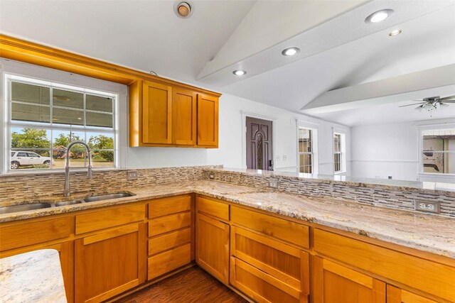 12212 Ballerstedt Rd, Elgin, TX 78621 - kitchen featuring vaulted ceiling, plenty of natural light, light stone countertops, recessed lighting, and brown cabinets