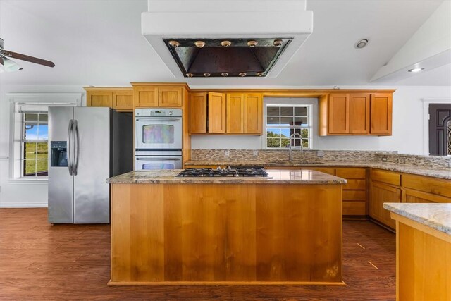 12212 Ballerstedt Rd, Elgin, TX 78621 - kitchen featuring appliances with stainless steel finishes, dark wood finished floors, light stone counters, a center island, and lofted ceiling