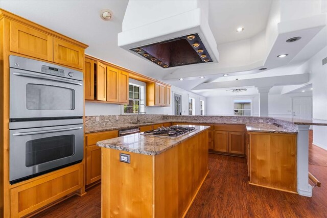12212 Ballerstedt Rd, Elgin, TX 78621 - kitchen with appliances with stainless steel finishes, a peninsula, extractor fan, light stone countertops, and a kitchen island