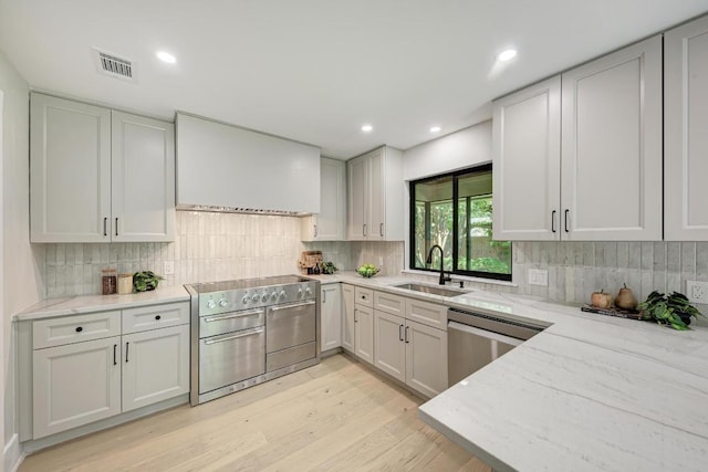 10507 Spicewood Pkwy, Austin, TX 78750 - kitchen featuring appliances with stainless steel finishes, light stone counters, light wood-type flooring, tasteful backsplash, and recessed lighting