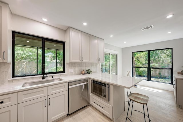 10507 Spicewood Pkwy, Austin, TX 78750 - kitchen with dishwasher, light wood finished floors, light stone countertops, backsplash, and recessed lighting