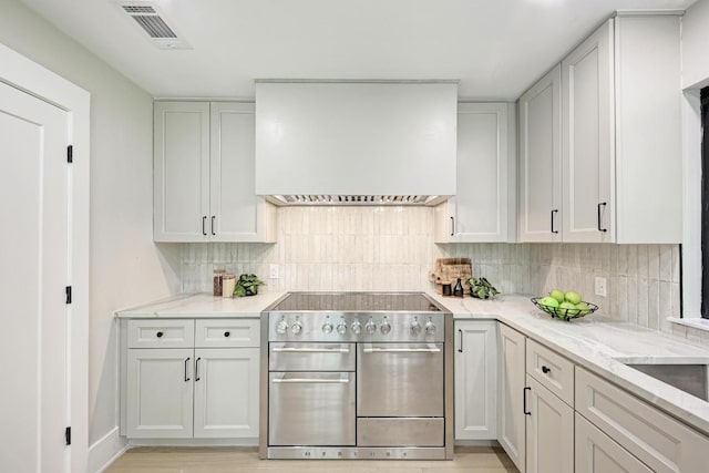 10507 Spicewood Pkwy, Austin, TX 78750 - kitchen with custom exhaust hood, stainless steel range, backsplash, and light stone countertops