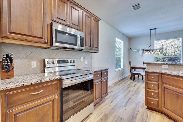 405 Alva Dr, Spicewood, TX 78669 - kitchen with stainless steel appliances, light wood-style floors, decorative backsplash, and light stone counters