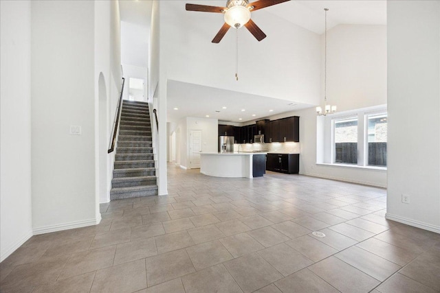 123 Pond View Pass, Buda, TX 78610 - unfurnished living room featuring a chandelier, high vaulted ceiling, ceiling fan, stairs, and light tile patterned flooring