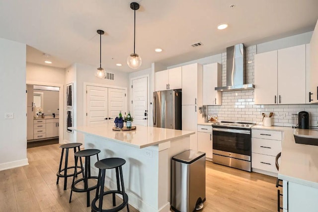 3101 Govalle Ave Unit 103, Austin, TX 78702 - kitchen with appliances with stainless steel finishes, wall chimney exhaust hood, a breakfast bar, light wood-style flooring, and recessed lighting