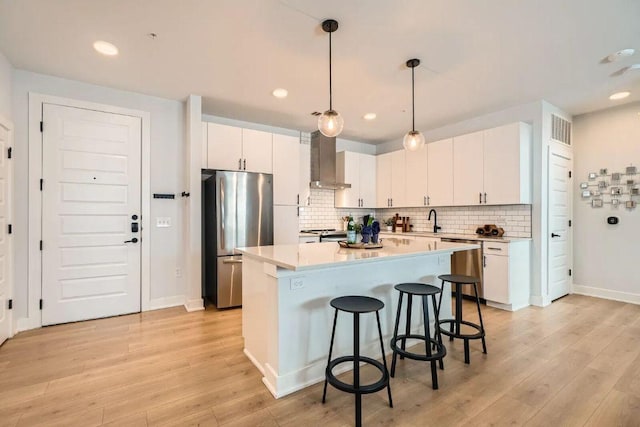 3101 Govalle Ave Unit 103, Austin, TX 78702 - kitchen featuring stainless steel appliances, wall chimney exhaust hood, a kitchen breakfast bar, light wood finished floors, and light countertops