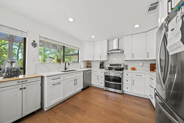 703 Stagecoach Trl, San Marcos, TX 78666 - kitchen featuring stainless steel appliances, wall chimney exhaust hood, light countertops, recessed lighting, and white cabinets
