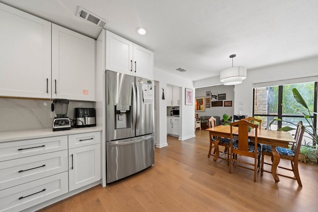 703 Stagecoach Trl, San Marcos, TX 78666 - kitchen with stainless steel fridge, light wood-type flooring, white cabinetry, backsplash, and light countertops
