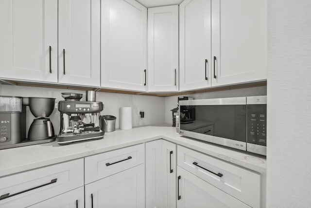 703 Stagecoach Trl, San Marcos, TX 78666 - kitchen with stainless steel microwave, white cabinetry, and tasteful backsplash