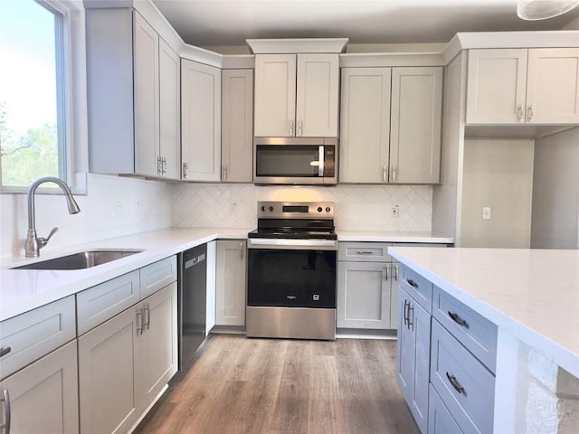 142 E Pauwela Ln, Bastrop, TX 78602 - kitchen with appliances with stainless steel finishes, tasteful backsplash, gray cabinetry, wood finished floors, and light stone counters