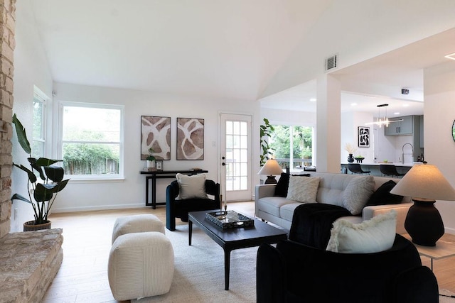 1402 Monica St, Austin, TX 78758 - living room with vaulted ceiling, light wood finished floors, and a chandelier