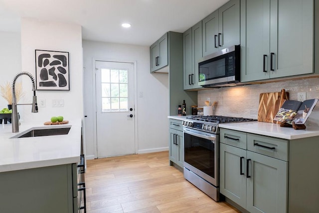 1402 Monica St, Austin, TX 78758 - kitchen with appliances with stainless steel finishes, light countertops, backsplash, light wood finished floors, and recessed lighting
