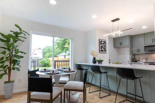 1402 Monica St, Austin, TX 78758 - kitchen featuring stainless steel microwave, gray cabinets, light countertops, light wood finished floors, and recessed lighting