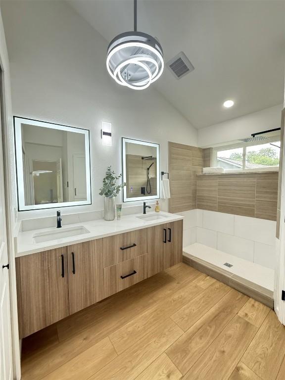 1402 Monica St, Austin, TX 78758 - bathroom featuring vaulted ceiling, walk in shower, double vanity, wood finished floors, and a chandelier