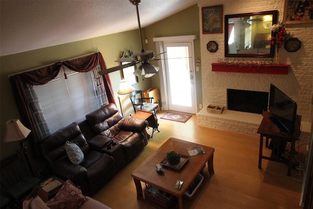 201 E Noton St Unit 105, Pflugerville, TX 78660 - living room featuring vaulted ceiling, wood finished floors, a ceiling fan, and a brick fireplace